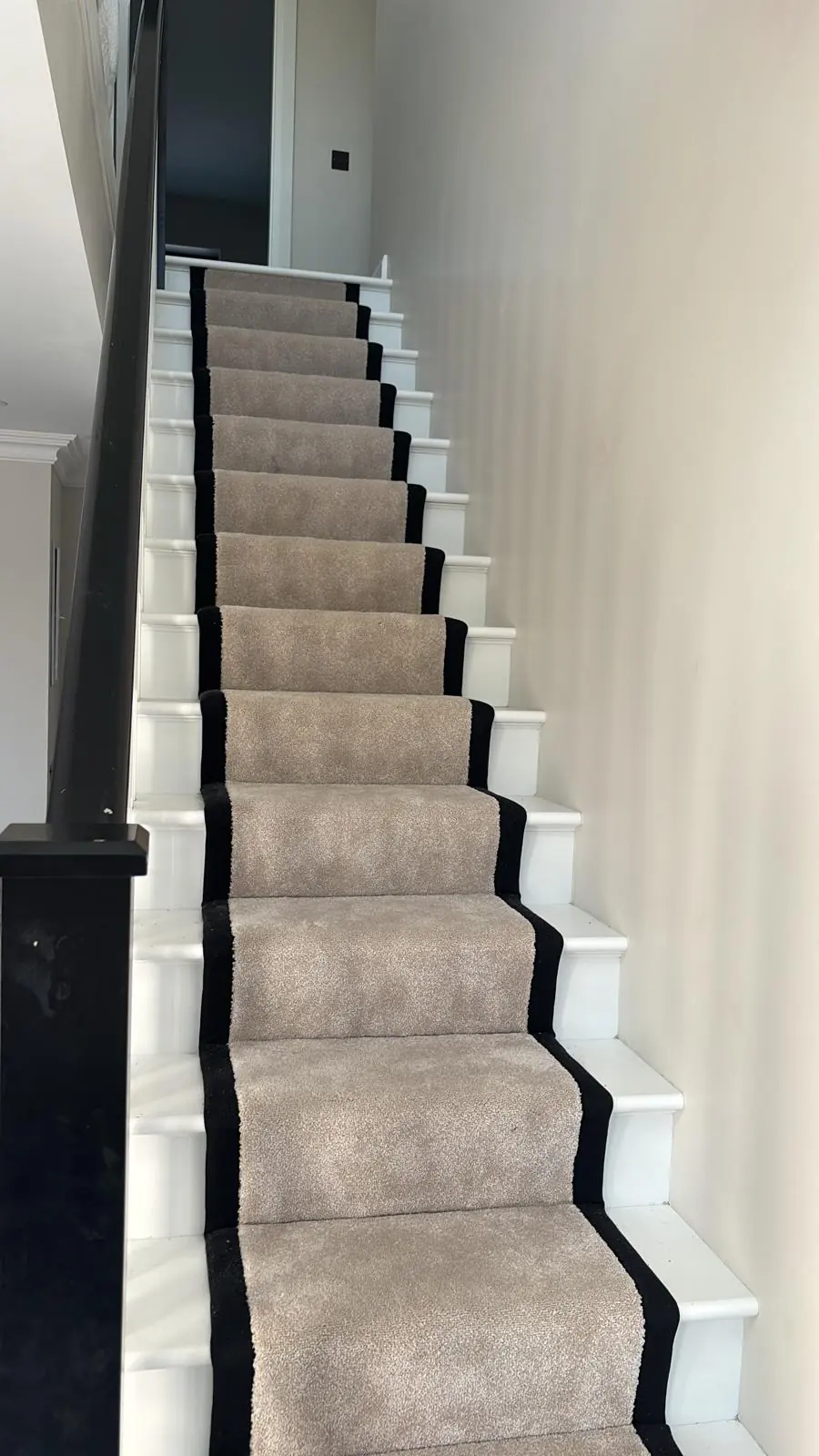 White staircase with grey carpet runner and dark handrail